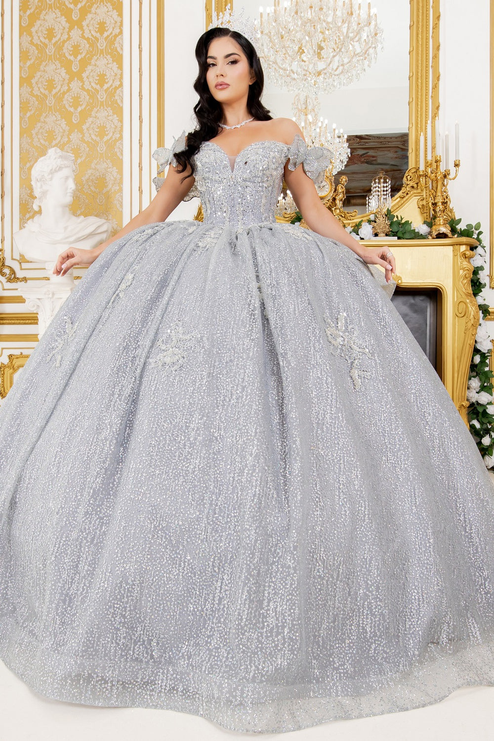 Woman in a silver ball gown in an elegant interior setting .BLISS 8120J emerald green quinceanera gown with lace appliqué and detachable butterfly – www.snkdress.com