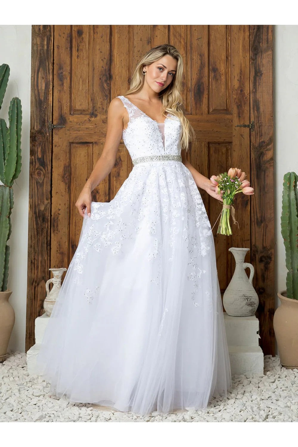 Woman in a white wedding dress holding a bouquet in front of a wooden door with cacti.plus size tulle ball gown dress with floral appliqué and pockets – www.snkdress.com