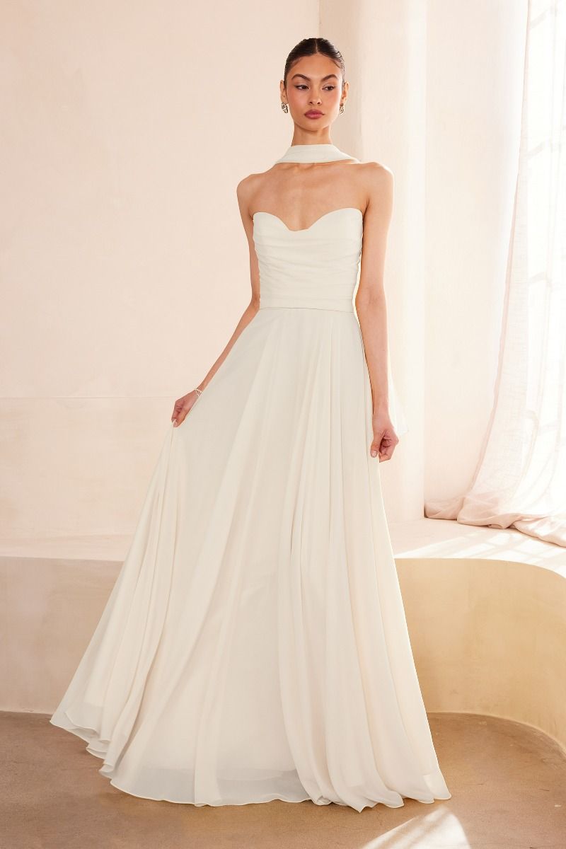 Woman wearing a strapless white wedding dress in a softly lit room.Strapless Chiffon A-Line Wedding Gown with Matching Neck Scarf by Ladivine T703W